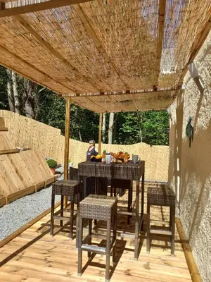 a wooden table and chairs under a wooden pergola at Maisonnette U Santu Ghjuvandria ou A Santa Ghjulia entre mer et Montagne in Volpajola