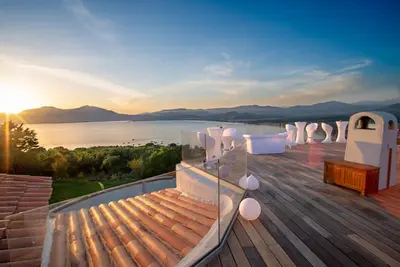a deck with a view of the water and mountains at U Tempu Persu in Grosseto-Prugna