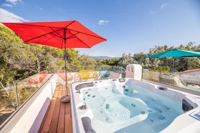 a hot tub on a deck with a red umbrella at U Tempu Persu in Grosseto-Prugna