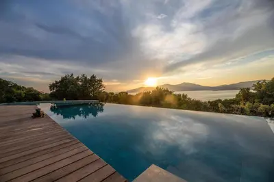 a large swimming pool with a sunset in the background at U Tempu Persu in Grosseto-Prugna