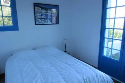 a bedroom with a white bed with blue walls and windows at Villa vue sur mer Corse Blanca Casa à PORTICCIO AJACCIO in Grosseto-Prugna