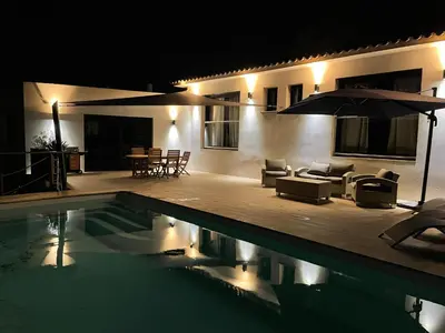 a pool with chairs and an umbrella next to a house at Villa Bianca in Zonza