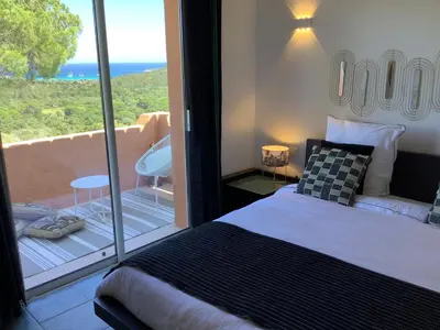a bedroom with a bed and a balcony with a view at Villa AZURA, vue panoramique et proche mer à Santa Giulia, piscine chauffée in Porto-Vecchio