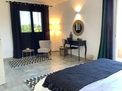 a bedroom with a bed and a desk with a mirror at Villa AZURA, vue panoramique et proche mer à Santa Giulia, piscine chauffée in Porto-Vecchio