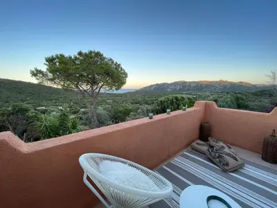 a balcony with a table and a chair and a view at Villa AZURA, vue panoramique et proche mer à Santa Giulia, piscine chauffée in Porto-Vecchio