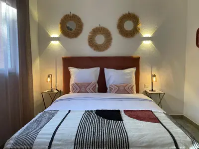 a bedroom with a bed with two mirrors on the wall at Villa AZURA, vue panoramique et proche mer à Santa Giulia, piscine chauffée in Porto-Vecchio