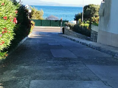 a person walking down a sidewalk next to the ocean at Appartement Ajaccio Sanguinaires in Ajaccio