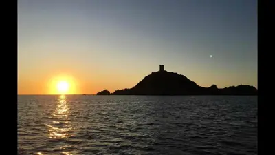 a lighthouse on an island in the ocean at sunset at Ajaccio appartement 4 couchages, climatisé a 150m de la plage route des sanguinaires, parking privé in Ajaccio