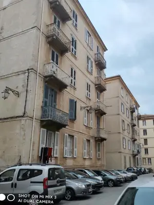a large building with cars parked in a parking lot at Bon'appart in Ajaccio