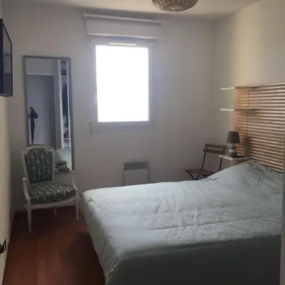 a bedroom with a bed and a chair and a window at Appartement T3 classé 3 étoiles vue mer avec terrasse ,plage 2 minutes à pied in Ajaccio