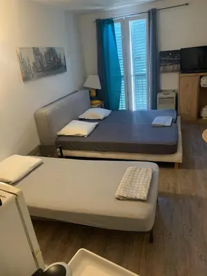 two beds in a small room with a window at AJACCIO CATHEDRALE AU COEUR DE LA CITEE IMPERIALE POUR 3 a 4 PERS PROCHE DES PLUS BELLES PLAGES ET DE TOUTES COMMODITES PORT A 2MN in Ajaccio