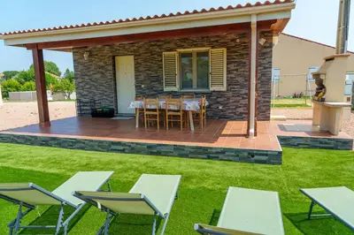 a patio with tables and chairs in a yard at Locations l'Inzecca in Ghisonaccia