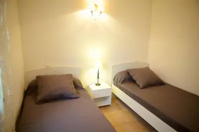 a bedroom with two beds and a lamp on the wall at Locations l'Inzecca in Ghisonaccia