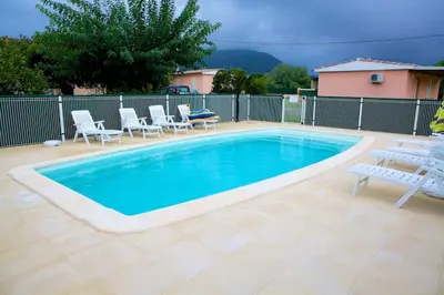 a large swimming pool with chairs and a table at Locations l'Inzecca in Ghisonaccia