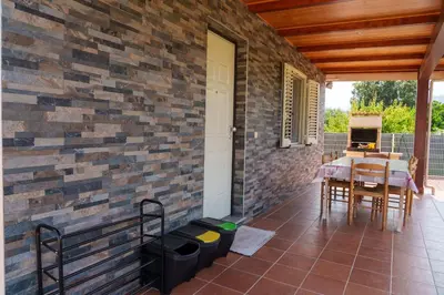 a patio with a brick wall and a table and chairs at Locations l'Inzecca in Ghisonaccia