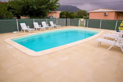 a swimming pool with white chairs and a table and chairs at Locations l'Inzecca in Ghisonaccia