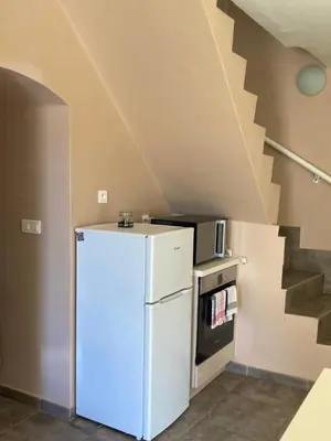 a white refrigerator in a room with a staircase at DUPLEX 4 PERSONNES Clim Wifi Parking in Partinello