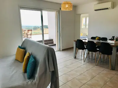 a living room with a couch and a table with chairs at Bel appartement dans villa à la campagne proche d’Ajaccio in Poggi