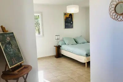 a bedroom with a bed and a painting on a table at Bel appartement dans villa à la campagne proche d’Ajaccio in Poggi
