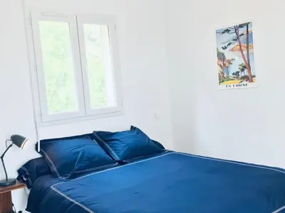 a blue bed in a bedroom with a window at Bel appartement dans villa à la campagne proche d’Ajaccio in Poggi