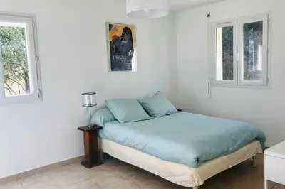 a bed in a room with two windows at Bel appartement dans villa à la campagne proche d’Ajaccio in Poggi
