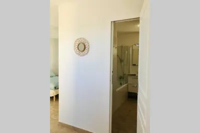 a bathroom with a white wall and a mirror at Bel appartement dans villa à la campagne proche d’Ajaccio in Poggi