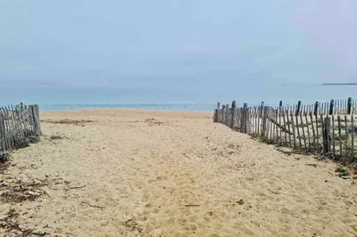 a sandy beach with a fence and the ocean at Bel appartement dans villa à la campagne proche d’Ajaccio in Poggi