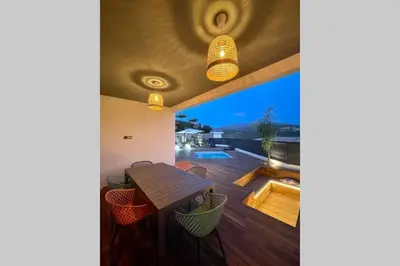 a house with a deck with a wooden table and a view at Villa moderne avec Piscine - Porticcio in Grosseto-Prugna