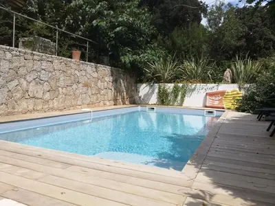 a swimming pool in a backyard with a stone wall at Villa Griseor in Porto-Vecchio