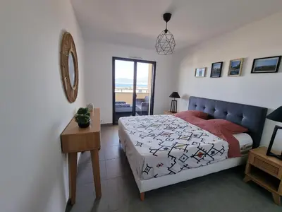 a bedroom with a bed and a table and a window at LoCorse - Superbe appartement T2 avec une belle vue mer in Grosseto-Prugna