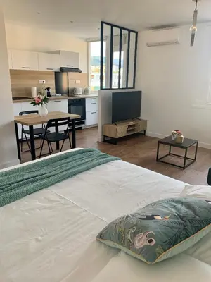a large white bedroom with a kitchen and a table at Joli studio spacieux in Ajaccio