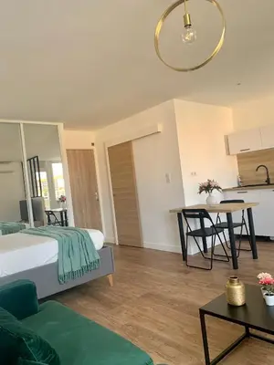 a bedroom with a bed and a table and a kitchen at Joli studio spacieux in Ajaccio