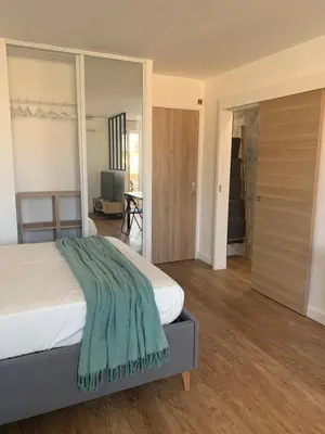 a bedroom with a bed with a green blanket on it at Joli studio spacieux in Ajaccio