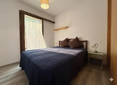 a bedroom with a bed with a blue comforter and a window at 8 ARBOUSIERS VILLA 12 in Bonifacio