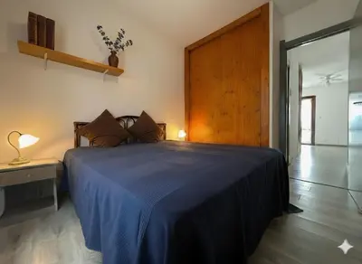 a bedroom with a blue bed with a wooden headboard at 8 ARBOUSIERS VILLA 12 in Bonifacio