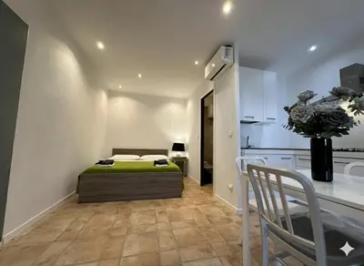 a bedroom with a bed and a table and a kitchen at 8 ARBOUSIERS VILLA 20 in Bonifacio