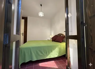 a bedroom with a bed with a green bedspread at 8 ARBOUSIERS VILLA 19 in Bonifacio