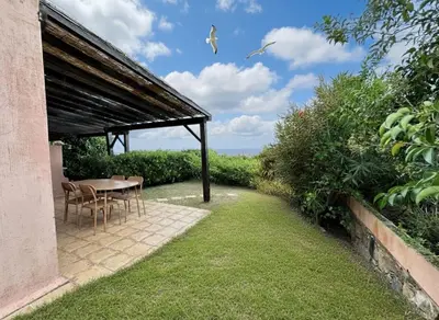 a patio with a table and chairs under a roof at 8 ARBOUSIERS VILLA 17 in Bonifacio