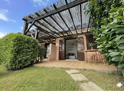 a patio with a table and chairs under a wooden roof at 8 ARBOUSIERS VILLA 16 in Bonifacio