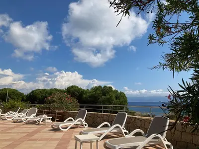 a row of white chairs sitting on a patio overlooking the ocean at Appartement VAIANA avec piscine en bord de mer in Ajaccio