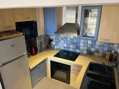 a kitchen with a refrigerator and a stove top oven at Appartement VAIANA avec piscine en bord de mer in Ajaccio
