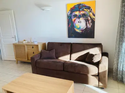 a living room with a couch and a painting of a dog at Appartement VAIANA avec piscine en bord de mer in Ajaccio