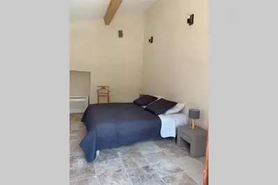 a bedroom with a bed with a blue comforter at Maison typique de campagne au cœur de la nature . in Sartène