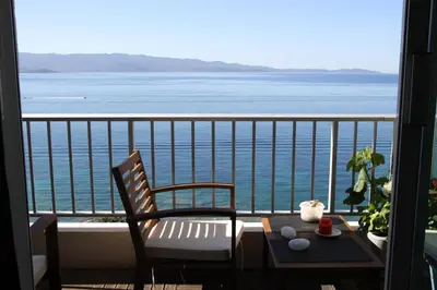 a balcony with a table and chairs and a view of the ocean at AjaccioPanoramicView in Ajaccio
