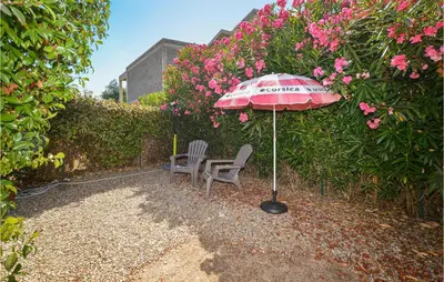 a patio with two chairs and an umbrella and flowers at 1 Bedroom Gorgeous Home In Venzolasca in Venzolasca