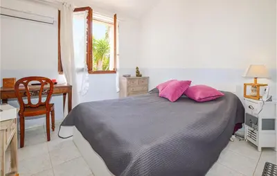 a bedroom with a bed with pink pillows and a desk at 1 Bedroom Gorgeous Home In Venzolasca in Venzolasca