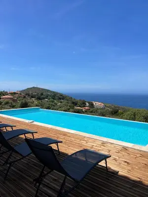 two chairs sitting on a deck next to a swimming pool at Villa Cargese in Cargèse