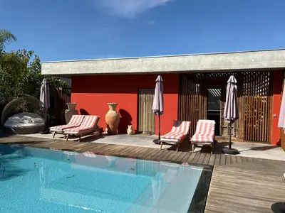 a pool with chairs and umbrellas next to a building at VILLA ALBA ROSULA in Ajaccio