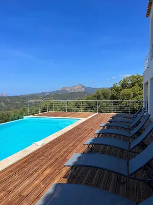 a deck with lounge chairs and a swimming pool at Appartement 4A villa cargese in Cargèse