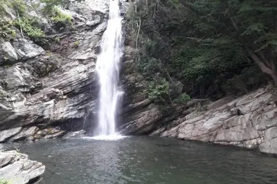 a waterfall on the side of a mountain with a pond at Appartement les pieds dans l'eau 300 m plage - 2 piscines in Linguizzetta